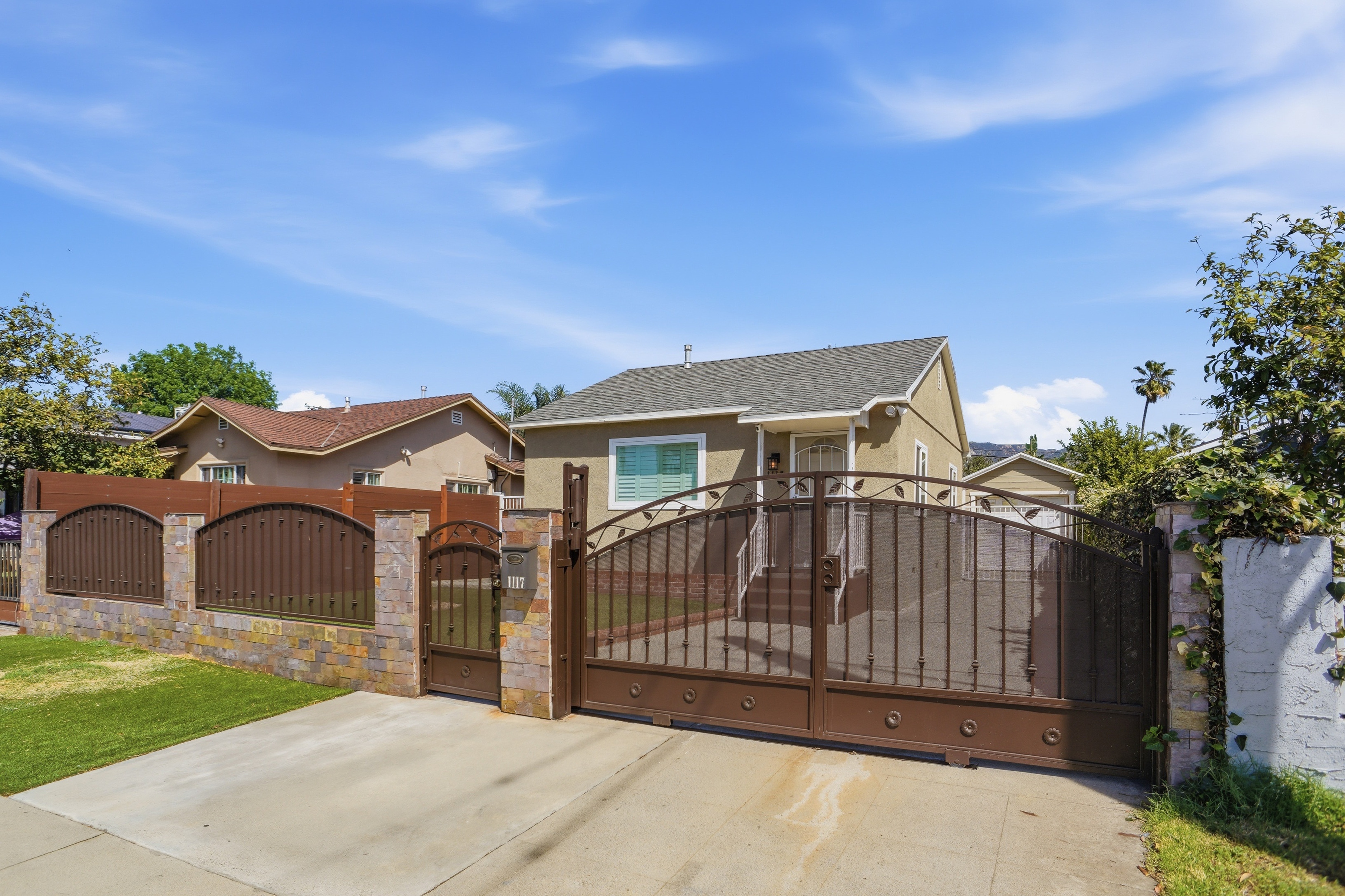 Gated front exterior with iron gates and stone pillars